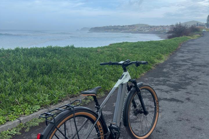 Bicycle on a coastal path with ocean and cloudy sky in the background.